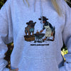 Person wearing a hoodie with a graphic of two dogs cooking on a grill and the text 'Paws and Patties'.
