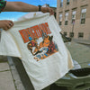 Person holding a t-shirt with graphic design in an urban setting