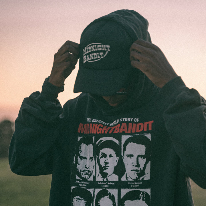 Person wearing a dark hoodie with 'Midnight Bandit' graphic design outdoors.